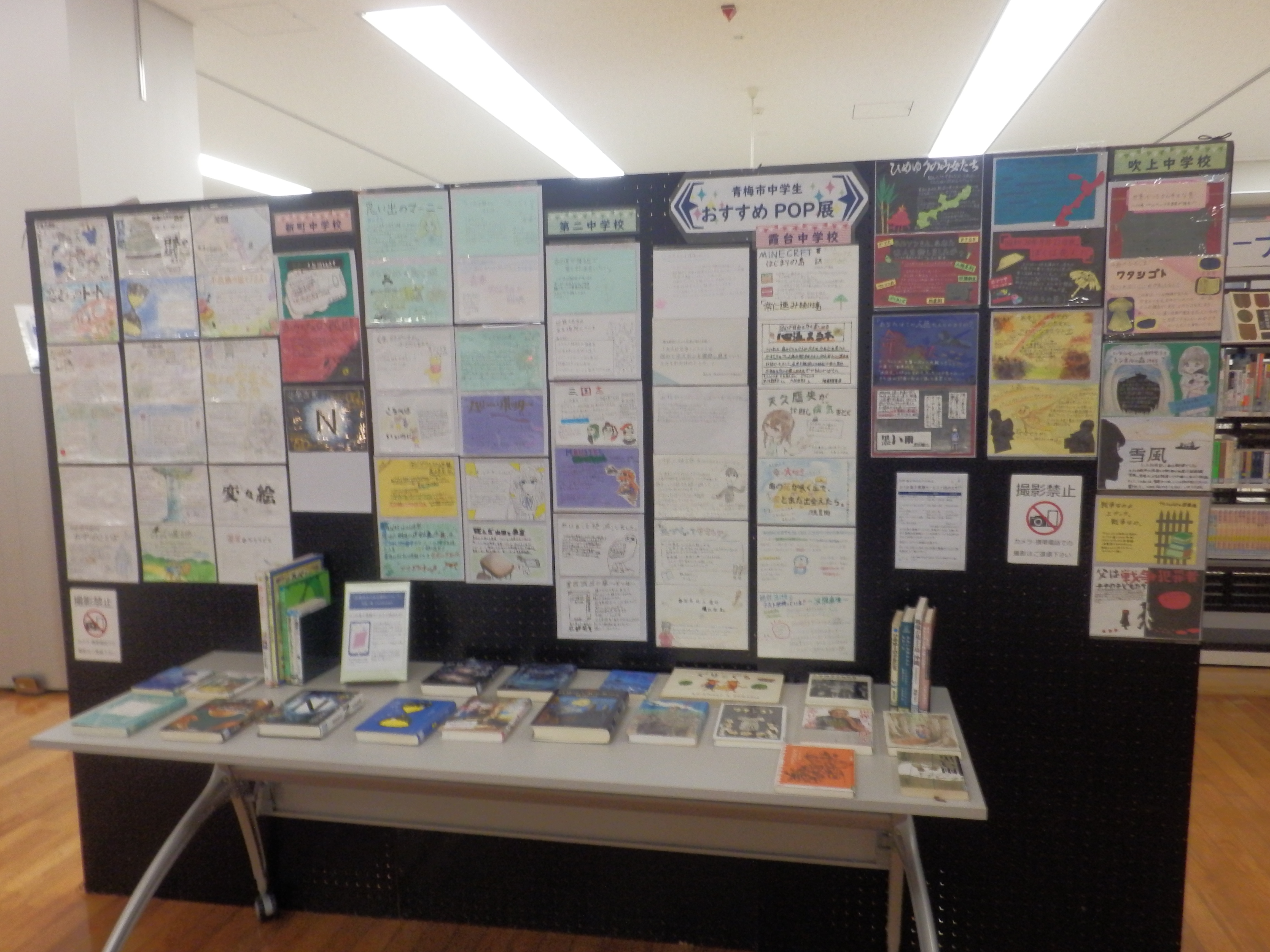 中学生おすすめ本POP展の写真。黒いパネルに中学生制作のPOPが飾られていて、机の上には紹介本が並べて展示されている。