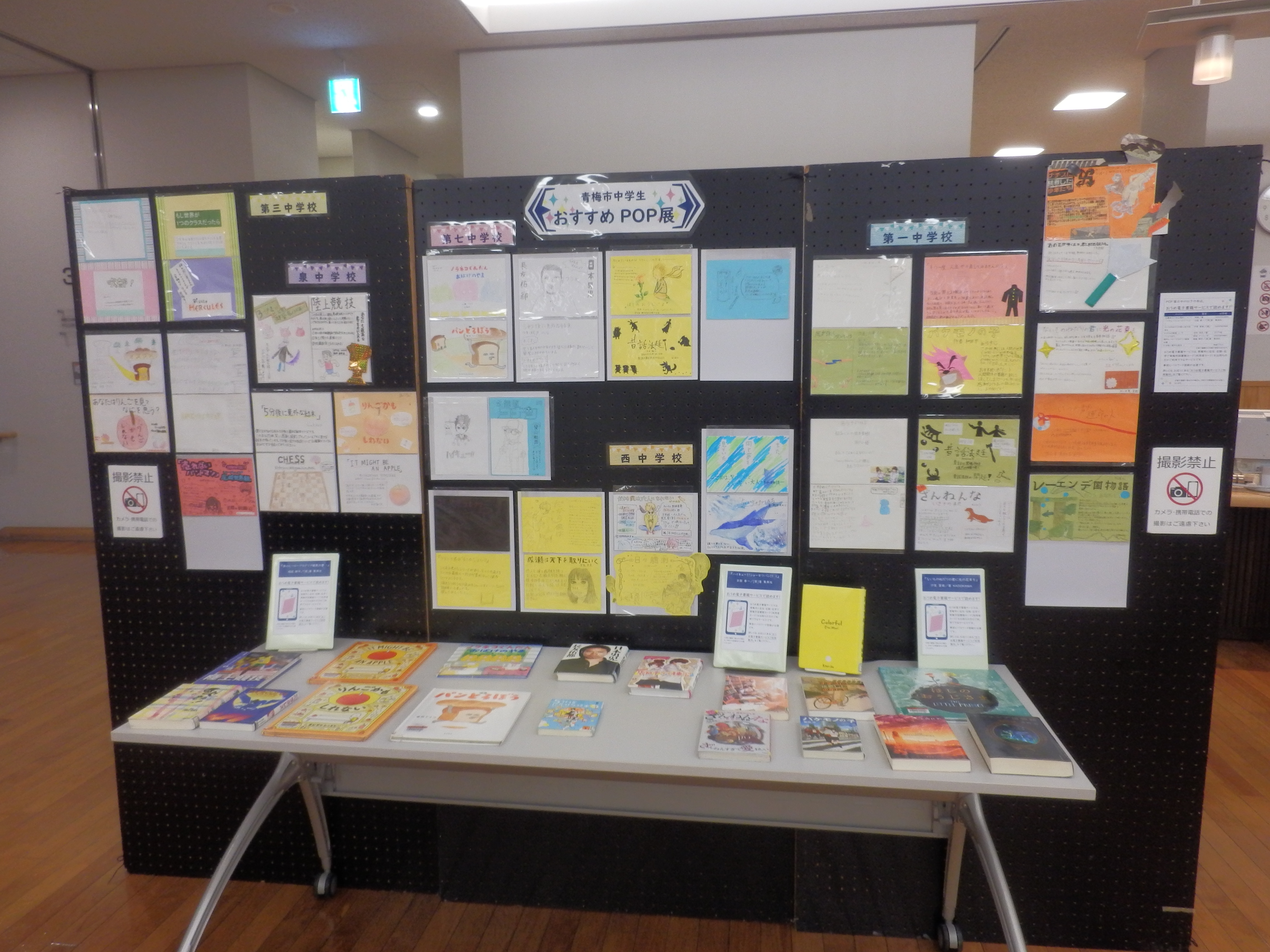 中学生おすすめ本POP展の写真。黒いパネルに中学生制作のPOPが飾られていて、机の上には紹介本が並べて展示されている。